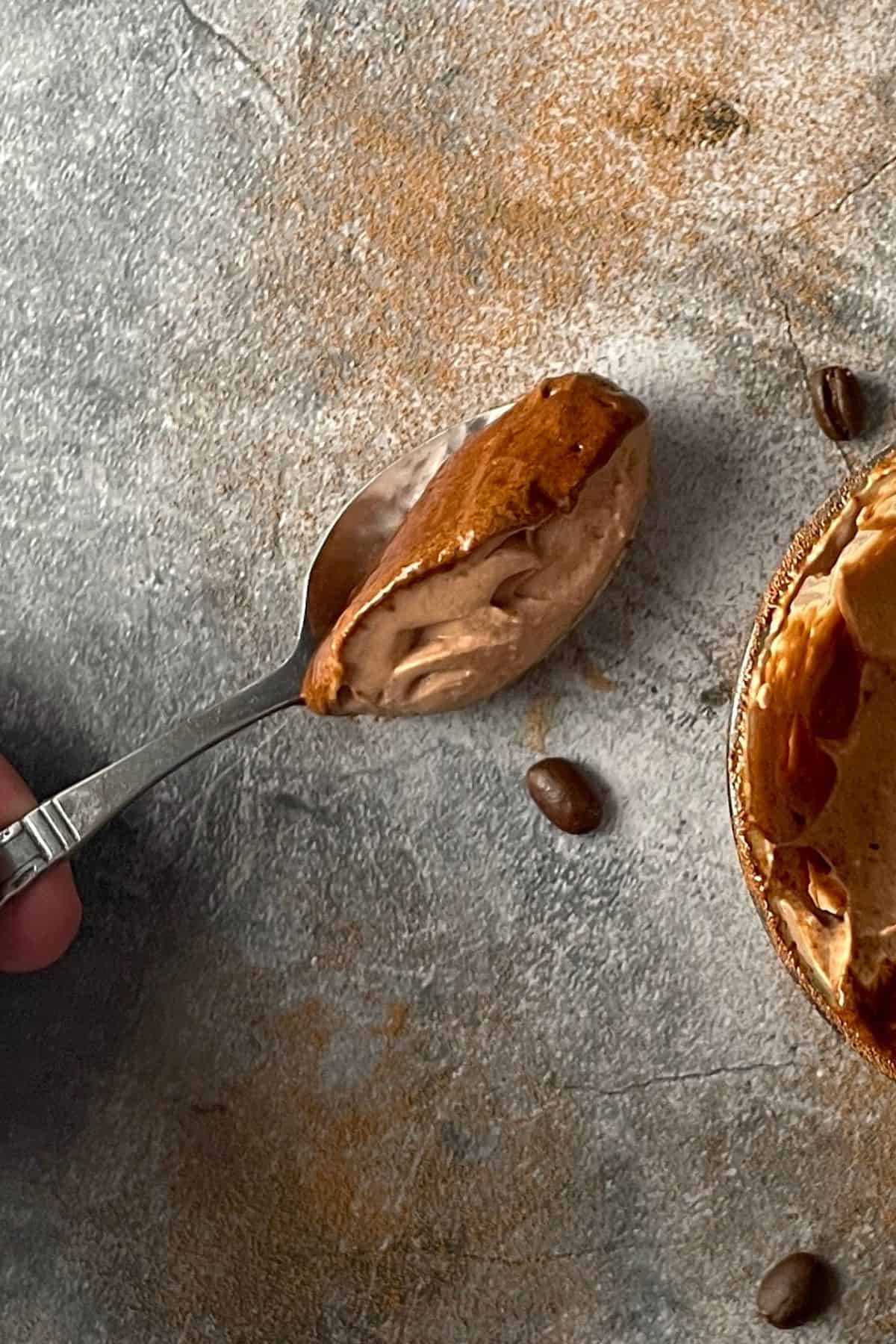 Spoonful of keto tiramisu mousse next to the tumbler and coffee beans.