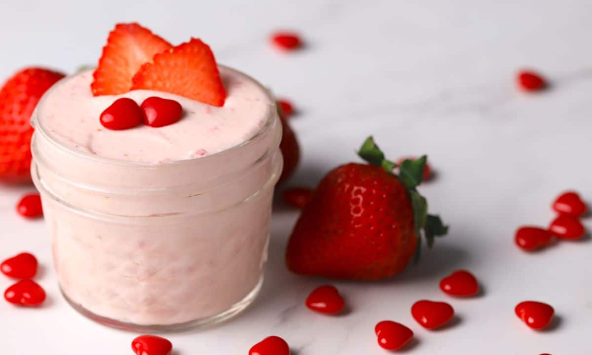 keto strawberry mousse in a small glass jar topped with strawberry slices and two cinnamon hearts.