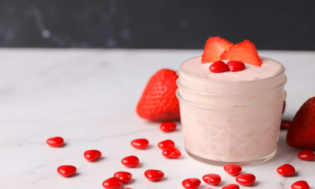 keto strawberry mousse in a small glass jar topped with strawberry slices and two cinnamon hearts.