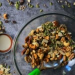 bowl with seeds and nuts and a spoon with more scattered on the countertop.