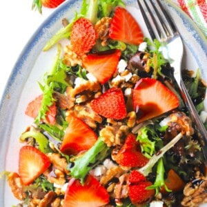 strawberry goat cheese salad on a blue rimmed platter with a fork.