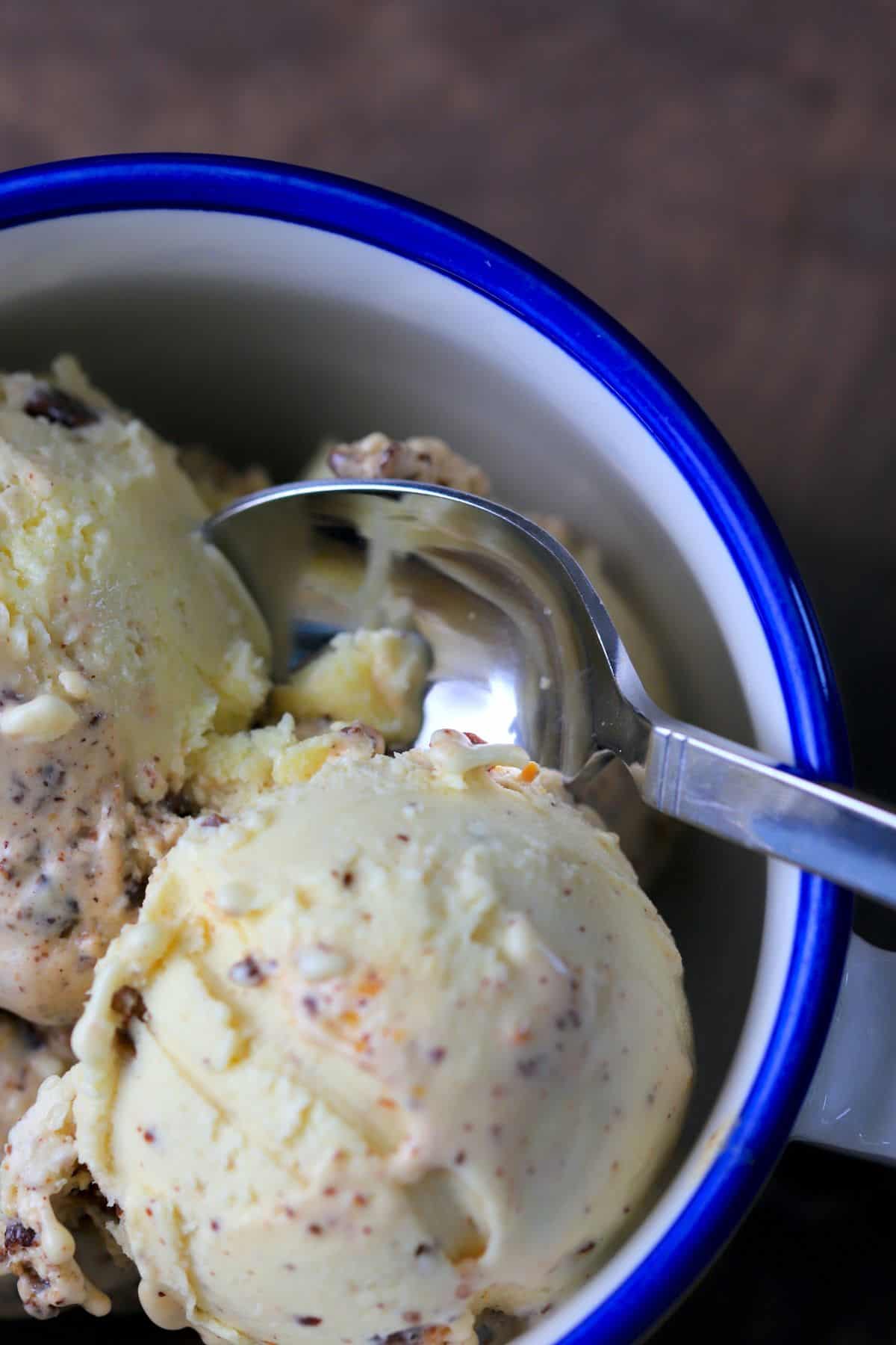 two scoops of ice cream in a yellow bowl with a blue rim.