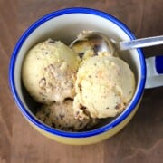 two scoops of ice cream in a yellow bowl with a blue rim.