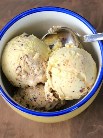 two scoops of ice cream in a yellow bowl with a blue rim.