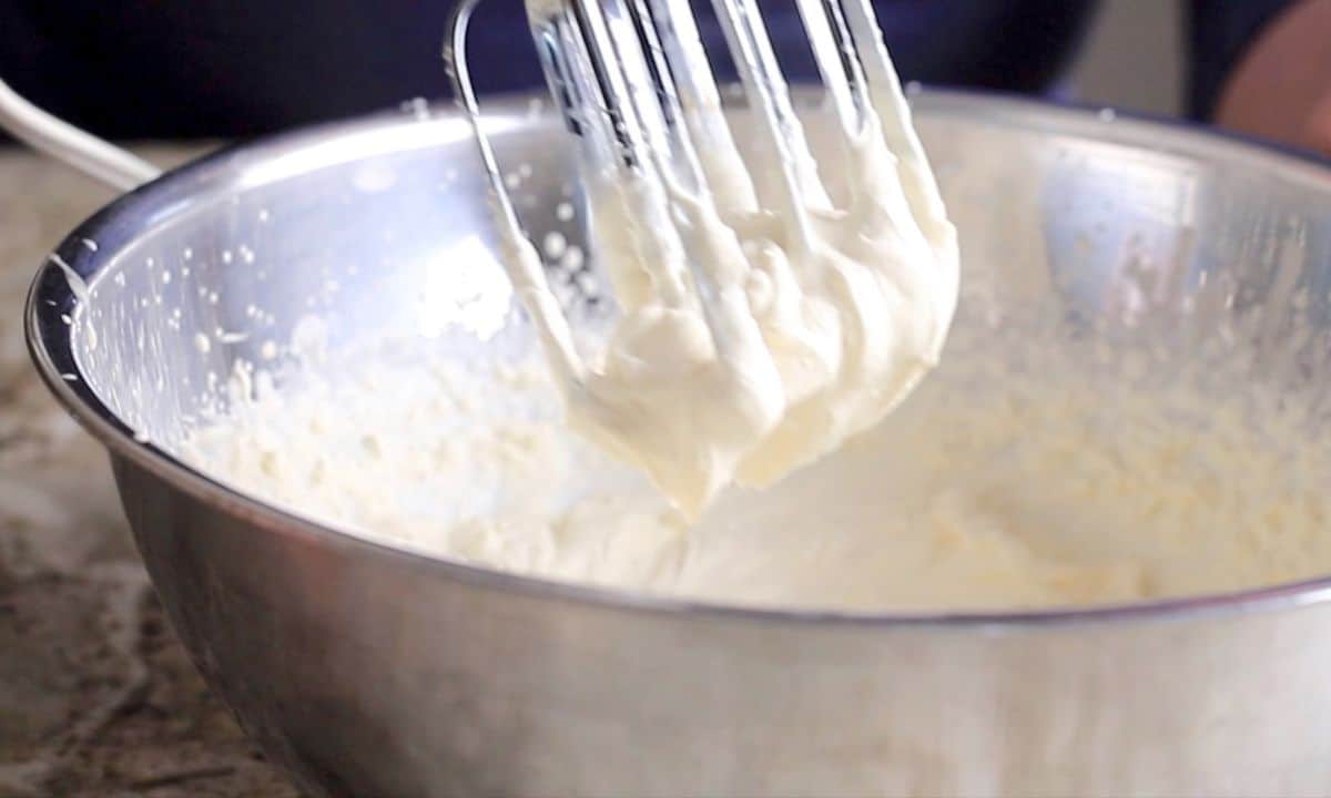 mix beaters above a bowl with whipped cream.