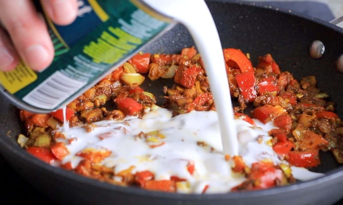 pouring coconut milk into the skillet pan.