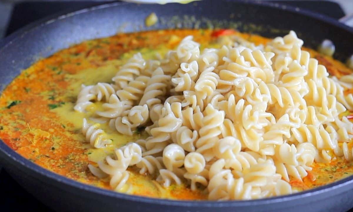 pasta in the curry sauce in the skillet pan.