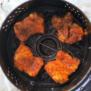 chicken thighs in air fryer basket.