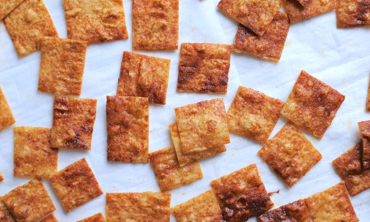 cinnamon toast crunch crackers spread out on a parchment sheet.