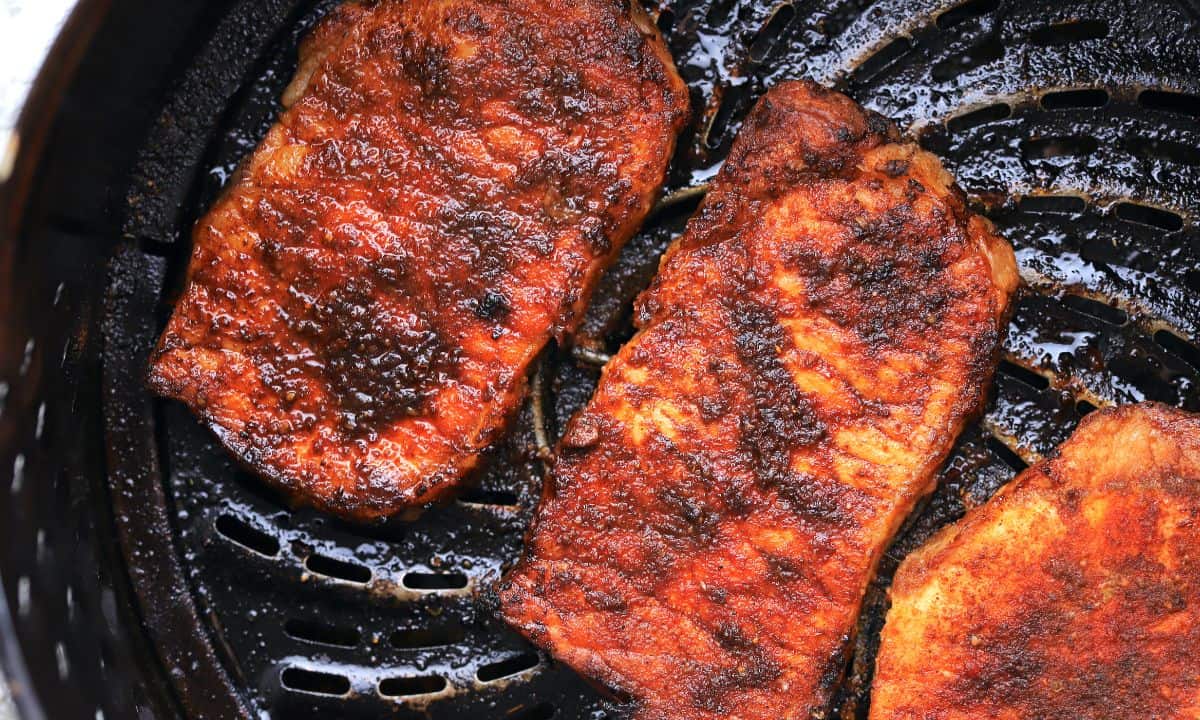 pork chops in an air fryer basket.