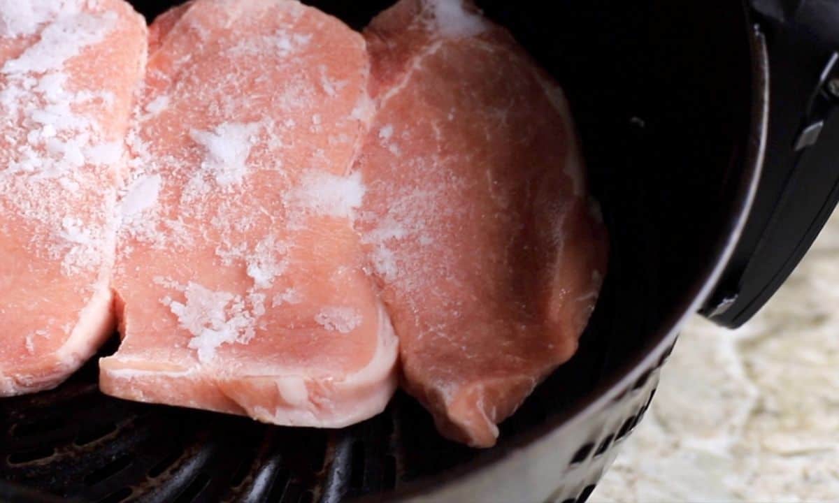 frozen pork chops in the air fryer basket.