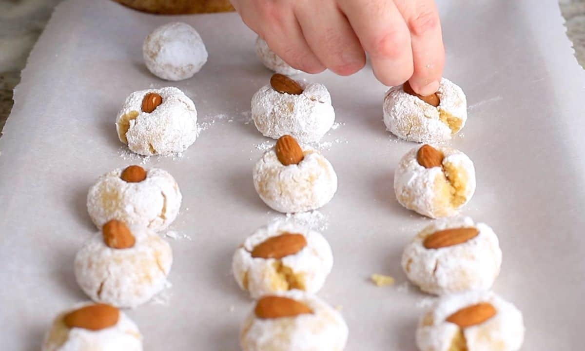 pressing an almond into the powdered cookie.