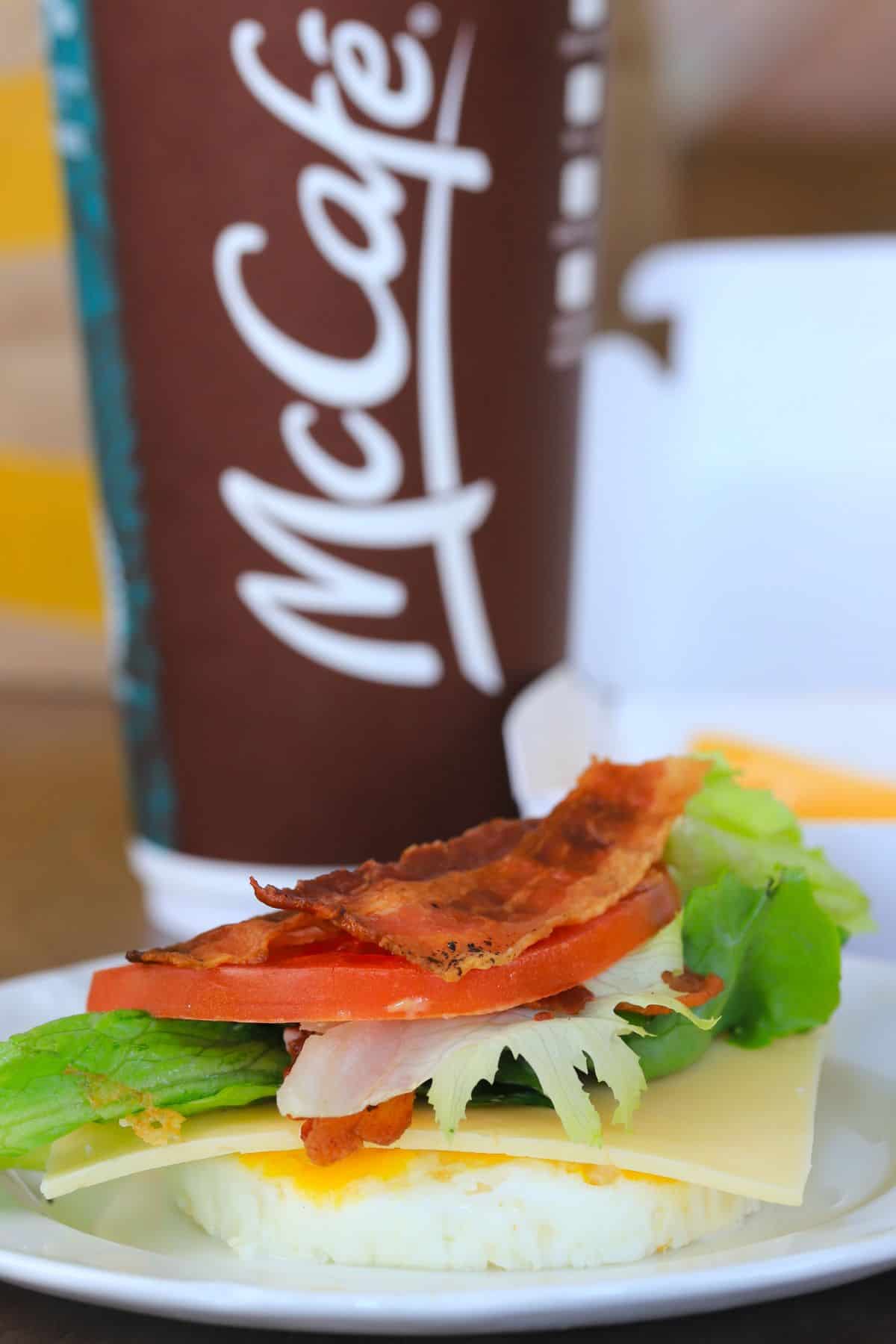 a round egg with a slice of gouda, lettuce, tomato and bacon.