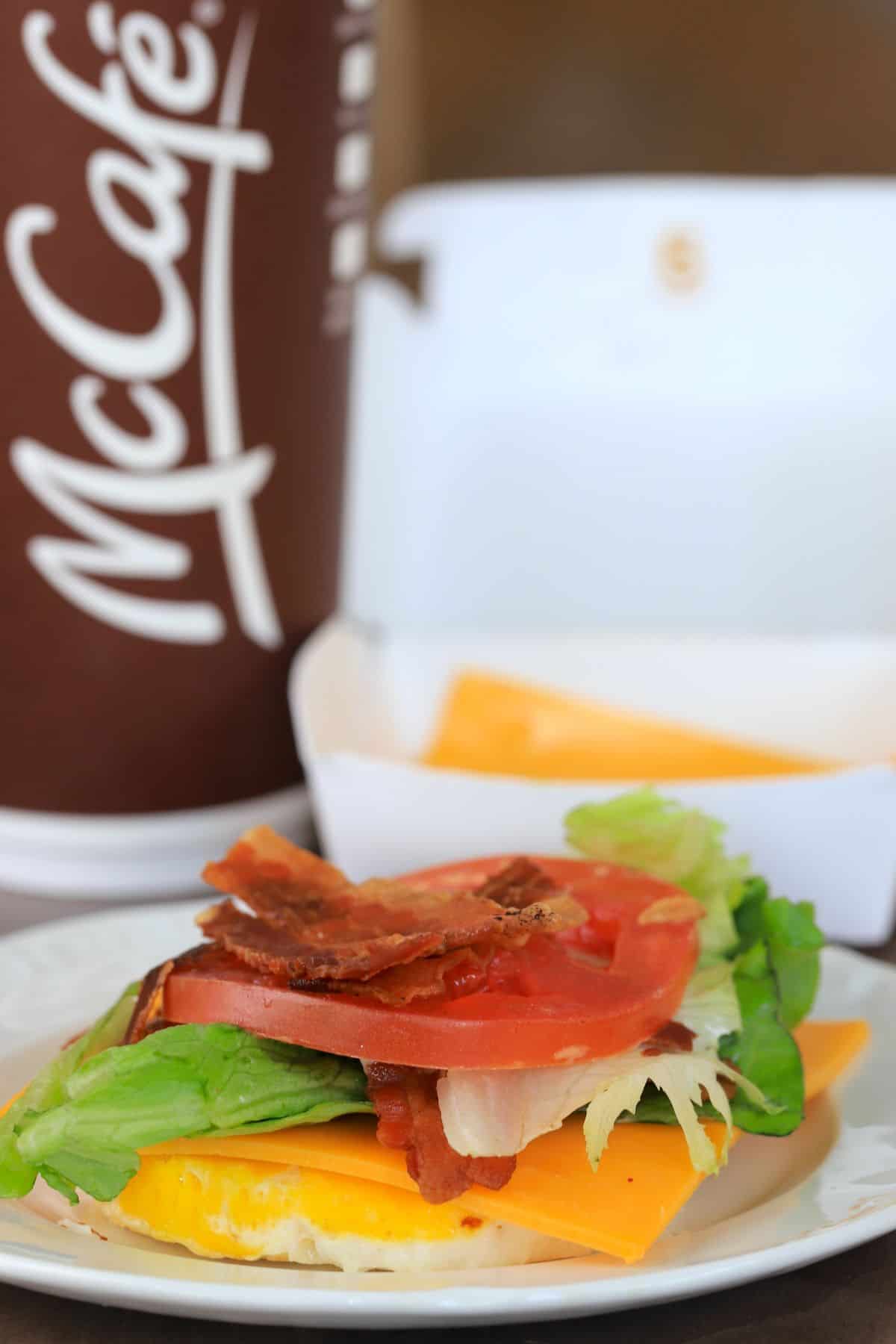 a round egg with a slice of cheddar cheese, lettuce, bacon and tomato.