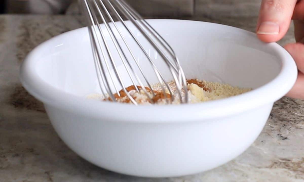 whisking the dry ingredients in a white bowl.