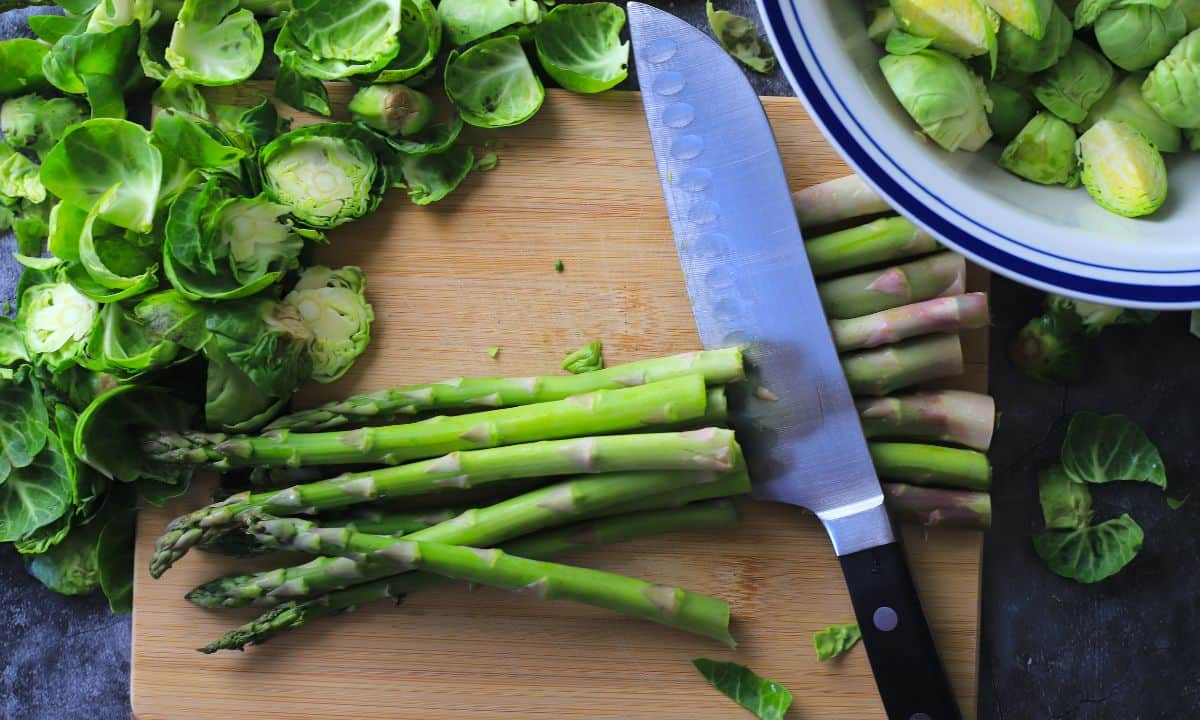Cutting asparagus on a cutting board.