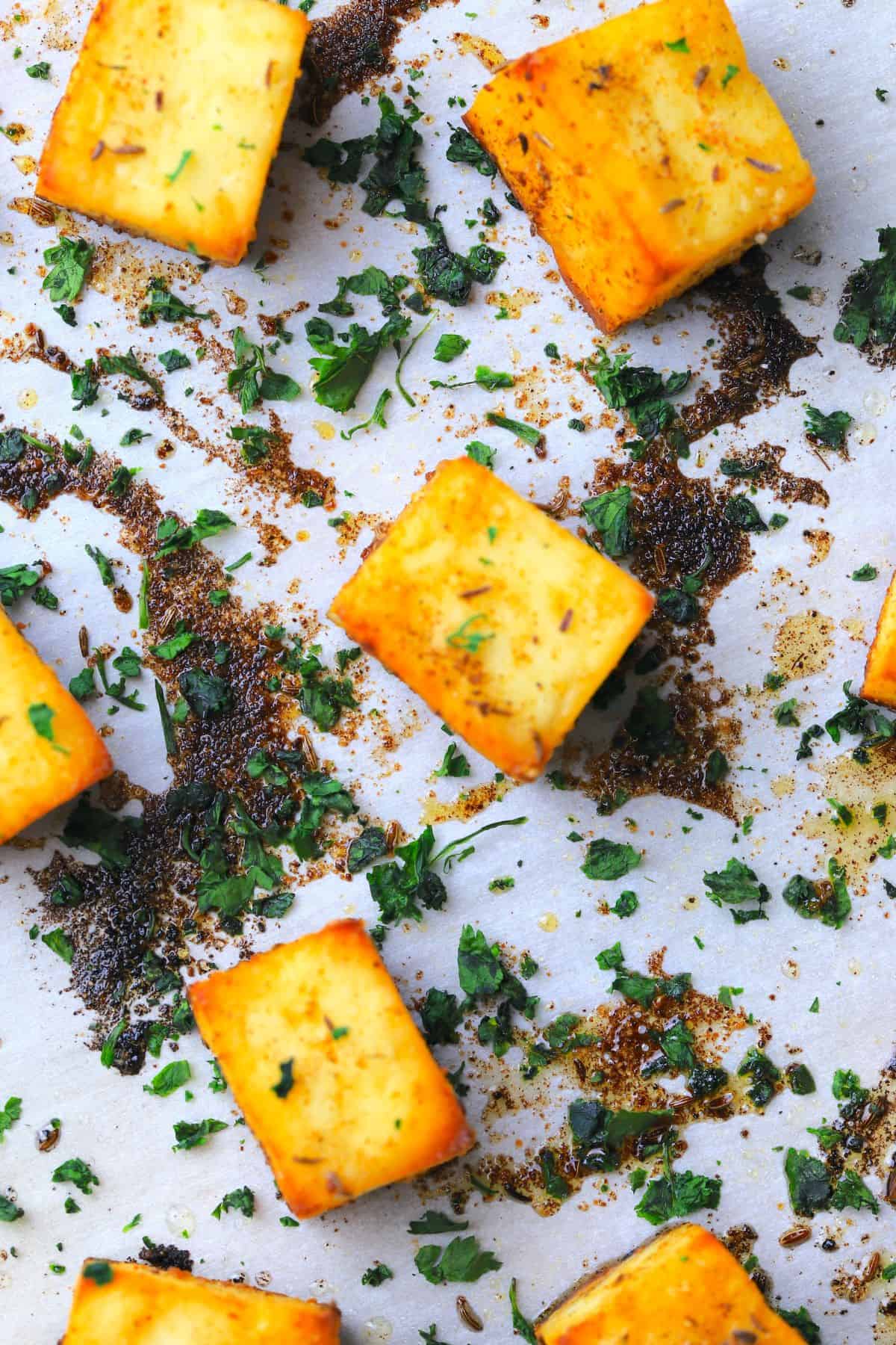 Roasted paneer on a baking sheet sprinkled with chopped cilantro.