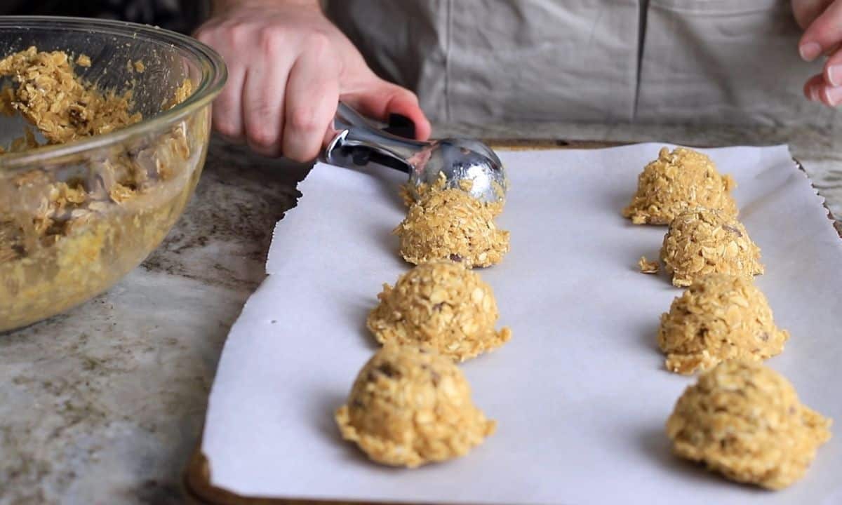 scooping cookie dough onto a parchment lined baking sheet.