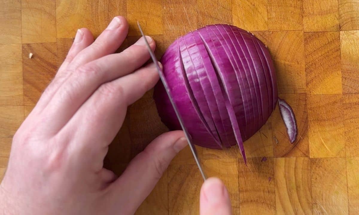 slicing red onion on a cutting board.