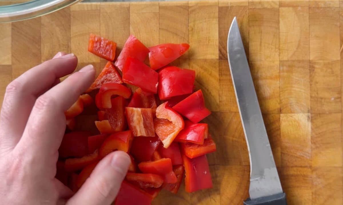 cutting red peppers on a cutting board.