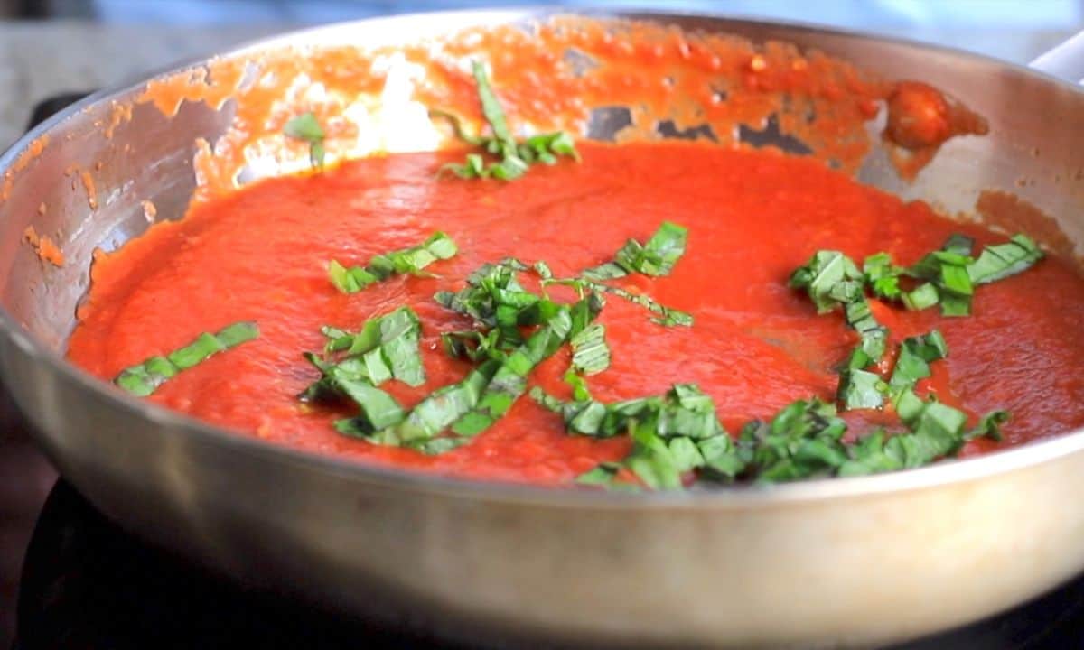 tomato sauce in a skillet with fresh basil.