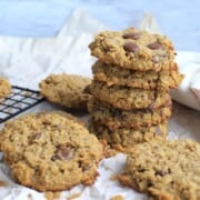 Sugar free oatmeal cookies on a cooling rack next to more cookies on crumpled parchment paper.