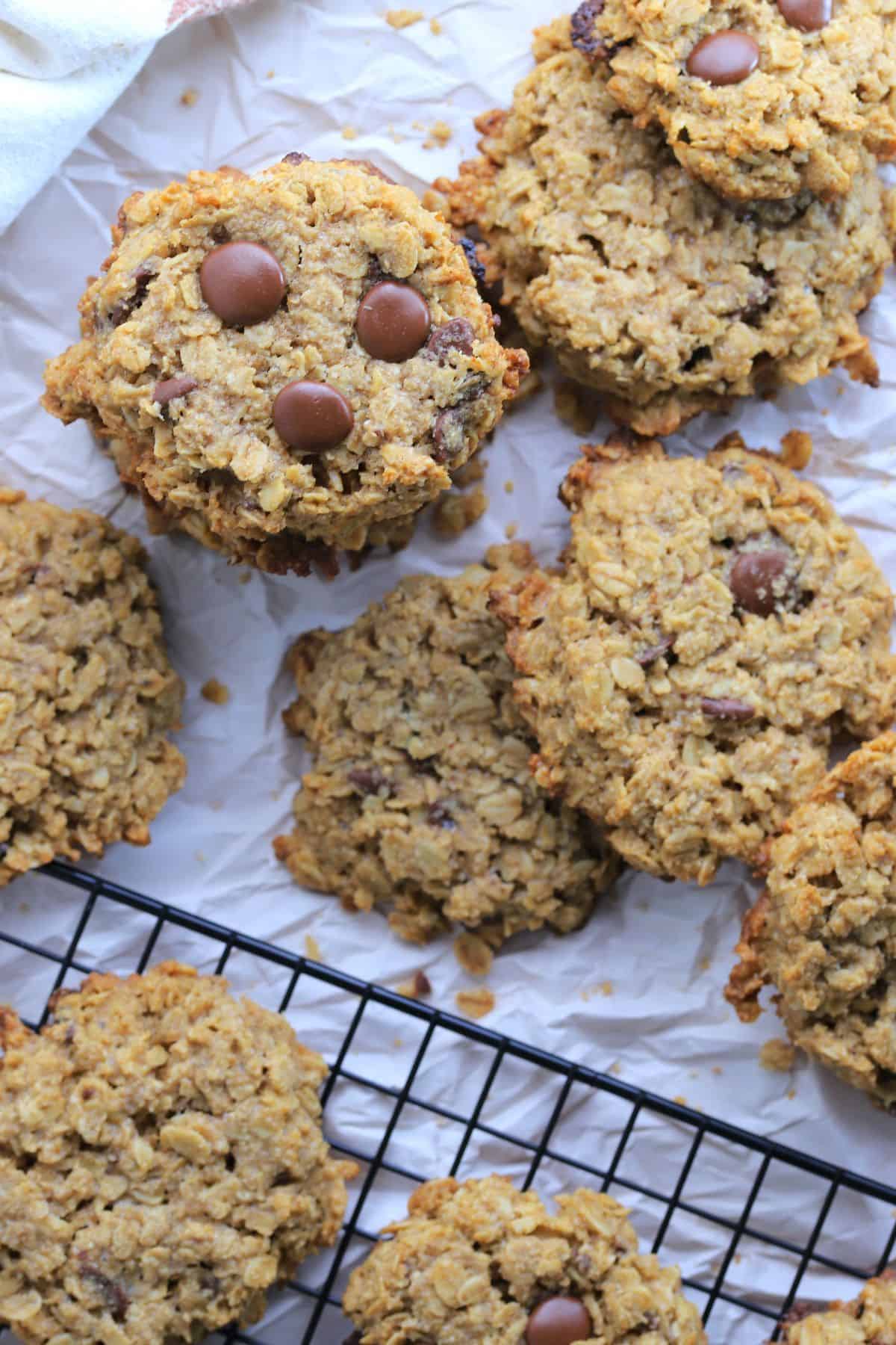 sugar free oatmeal cookies on a cooling rack next to more cookies on crimpled parchment.