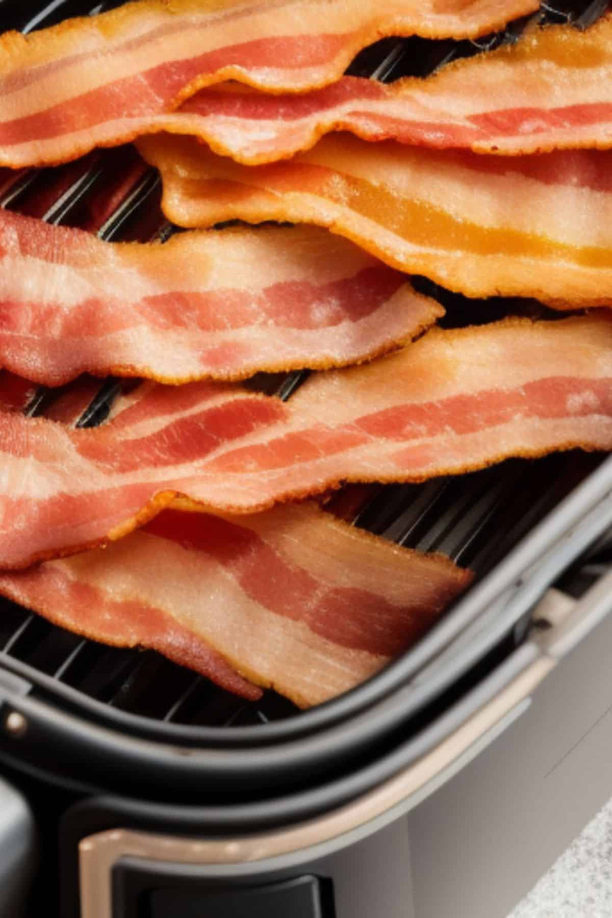 strips of cooked bacon in an air fryer basket.