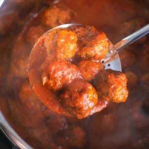 meatballs in the instant pot with a laddle holding 6 meatballs.