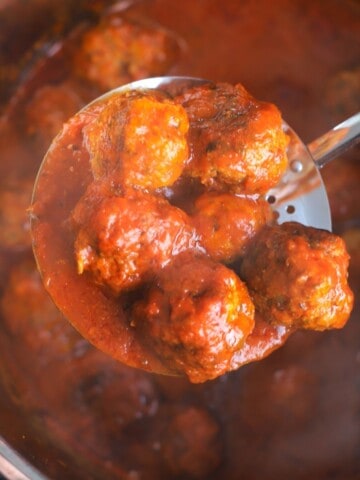 meatballs in the instant pot with a laddle holding 6 meatballs.