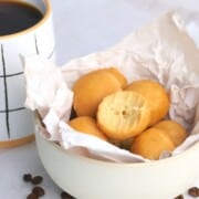 Maple protein coffee bites in a bowl lined with crumpled parchment paper next to a cup of coffee.