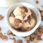 moose tracks ice cream in a small white bowl next to an ice cream scoop.