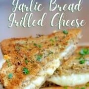 garlic bread grilled cheese sandwich cut in half with oozing cheese garnished with chopped parsley flakes.