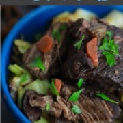 Blue bowl with short ribs topped with carrots and celery.