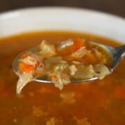 bowl of chicken soup with spoonful of soup.