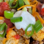 loaded cauliflower nachos topped with salsa, sour cream and green onions.