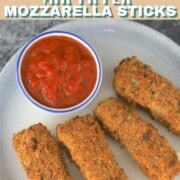 4 mozzarella sticks on a plate with a side of ketchup.