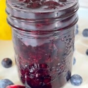 jar of blueberry pie filling with a spoon on the side full of the filling.
