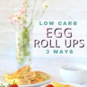 egg roll ups piled on a platter with a single egg roll up on a plate with a strawberry and a fork.