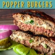 stacked jalapeno popper burger halves on a lettuce lined plate next to red onions and pickles.