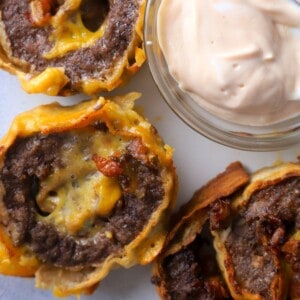 Cheeseburger roll ups on a dish next to a small bowl with dipping sauce.