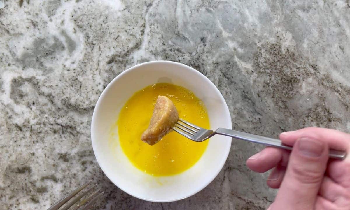 dipping the chicken nuggets in the whisked eggs.