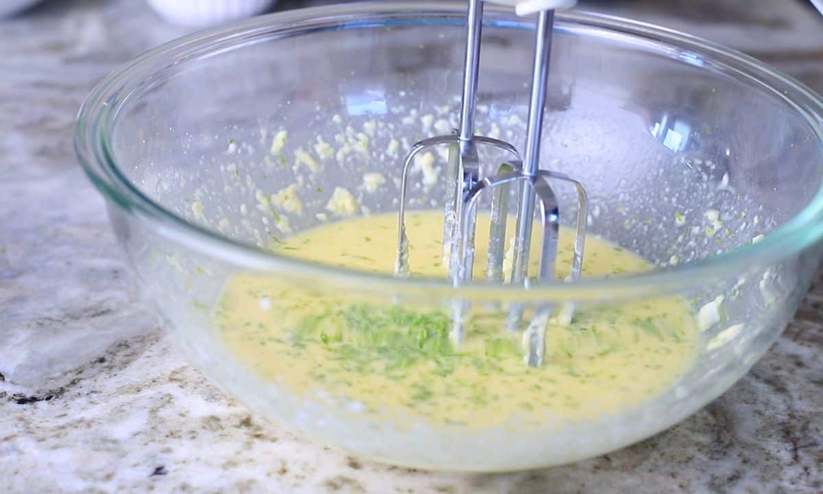 large glass bowl with wet ingredients and an electric mixer.