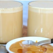 two glass mugs of peanut butter coffee with a small bowl of peanut butter in front.
