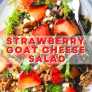 strawberry goat cheese salad on a blue rimmed platter with a fork.