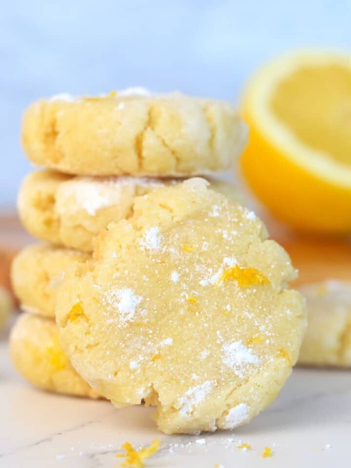 stack of sugar free lemon cookies in front of a half lemon and a reamer.