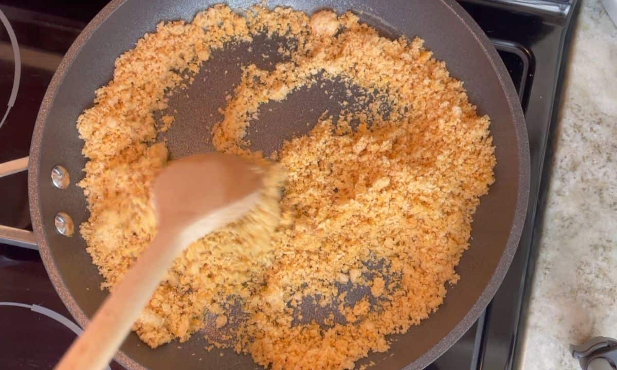 toasting the pork rind crumbs in a frying pan on the stove.