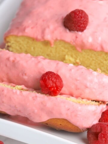 almond raspberry cake with raspberry icing cut into slices.