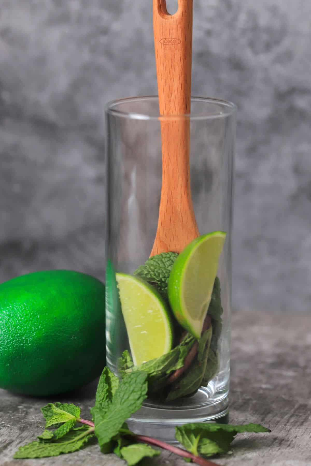 muddling the limes in a tall glass.
