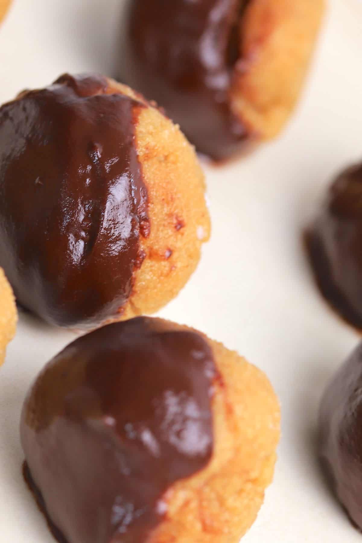 peanut butter bliss balls dipped in chocolate on a white plate.